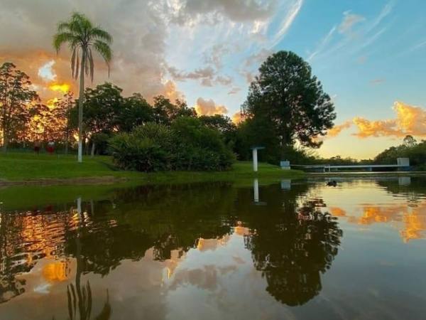Lago do Parque Eldorado no pôr do sol, com as árvores refletidas na água