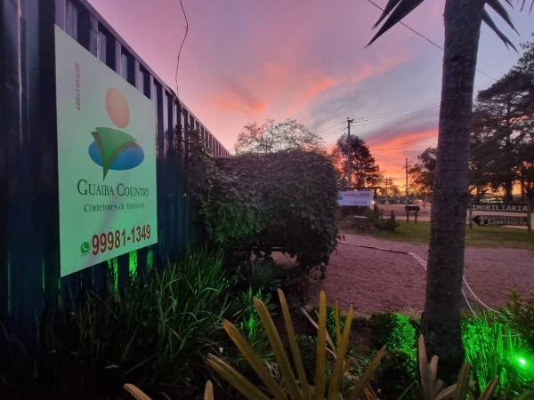 Fachada da Guaíba Country Imóveis ao entardecer, com a placa iluminada